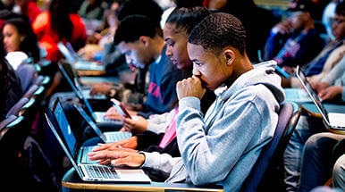 African American boy on laptop in lecture hall