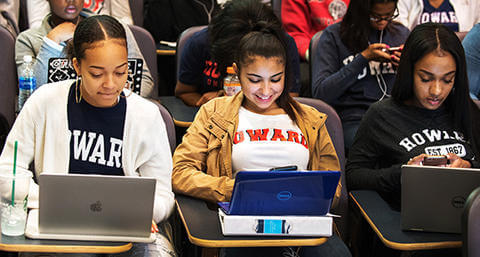 Three african american girls in howard university sweatshirts on their laptops