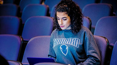 girl in bison sweatshirt looking at laptop